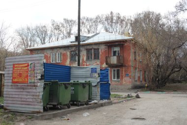Russia, Novosibirsk 05.05.2019: garbage containers in a landfill near an old dirty apartment building scattered waste