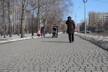 Russia, Novosibirsk 24.03.2019: women with children walk on the sidewalk in the Park in the spring