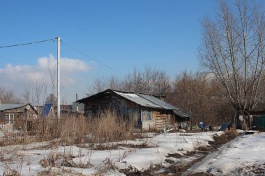 Kışın köydeki çitlerin arkasında terk edilmiş eski ahşap bir ev.