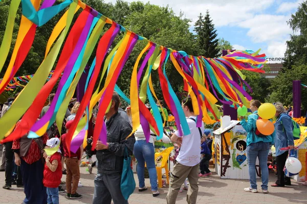 Rusya, Novosibirsk, 06.30.2019: çocuklu mutlu insanlar eğlence için parlak kurdelelerle süslenmiş bir şehir tatilinde yürüyorlar