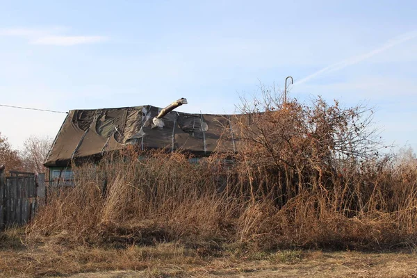 秋に乾いた草で覆われた放棄された村の古い荒廃した木造住宅 — ストック写真