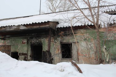 Kırık camları olan terk edilmiş bir bina. Kışın kar altında tehlikeli kalıntılar.