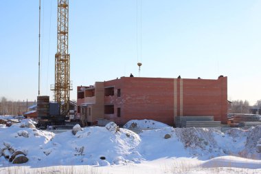 Kışın şantiyesinde vinci olan tuğladan bir ev.