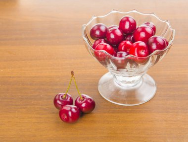 İki cherrie ile ahşap bir masa üzerinde beyaz bir fincan tatlı kiraz