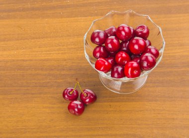 İki cherrie ile ahşap bir masa üzerinde beyaz bir fincan tatlı kiraz