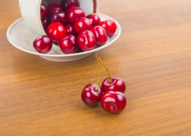İki cherrie ile ahşap bir masa üzerinde beyaz bir fincan tatlı kiraz