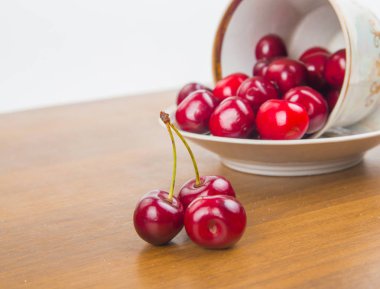 İki cherrie ile ahşap bir masa üzerinde beyaz bir fincan tatlı kiraz