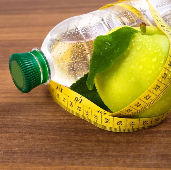 Apple core, bottled water for healthy life over a wooden backgro — Stock Photo, Image