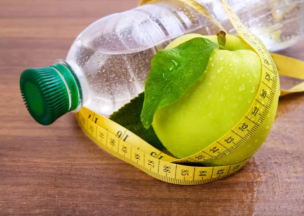 Apple core, bottled water for healthy life over a wooden background — Stock Photo, Image