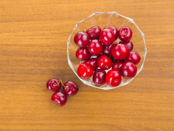 Cerejas doces em uma xícara branca em uma mesa de madeira com duas cerejas — Fotografia de Stock