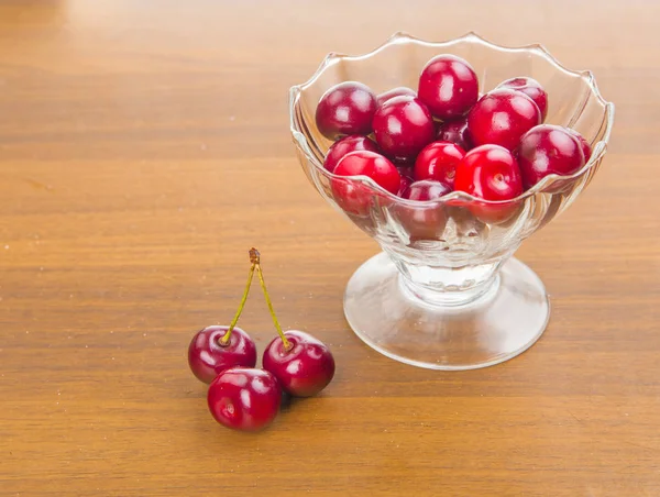 İki cherrie ile ahşap bir masa üzerinde beyaz bir fincan tatlı kiraz