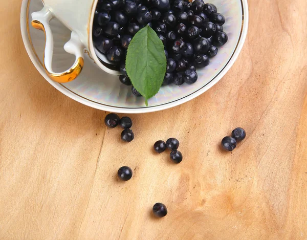 Blaubeeren, Johannisbeere mit Blatt in Schale, Tasse auf Holzgrund — Stockfoto