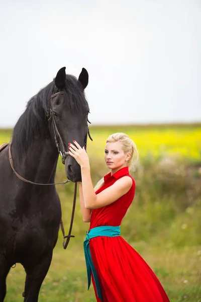 Modny blond kobieta na koniu w słoneczny dzień. Długie włosy. — Zdjęcie stockowe