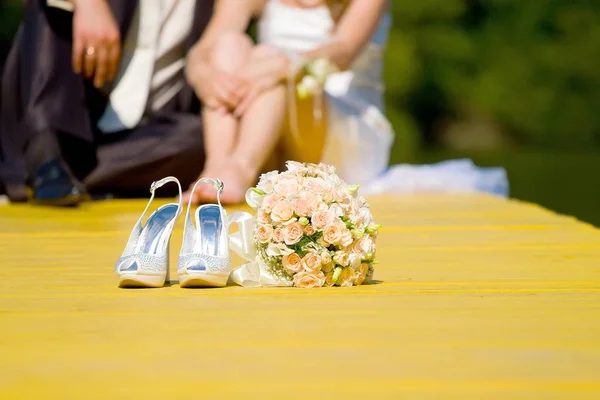 Παπούτσια Γάμου και ροδαλή ανθοδέσμη της νύφης και το ζευγάρι στην θαμπάδα — Φωτογραφία Αρχείου