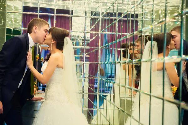 Unga brudparet kyssas i rummet med speglar — Stockfoto