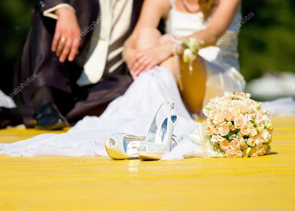 wedding shoes and rose bouquet of bride and couple in blur