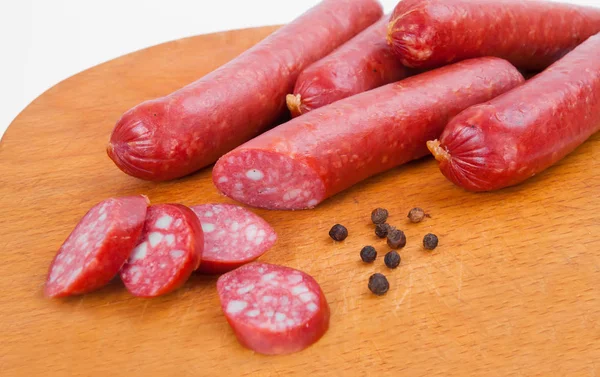 Smoked sausages on wooden desk isolated on white background — Stock Photo, Image