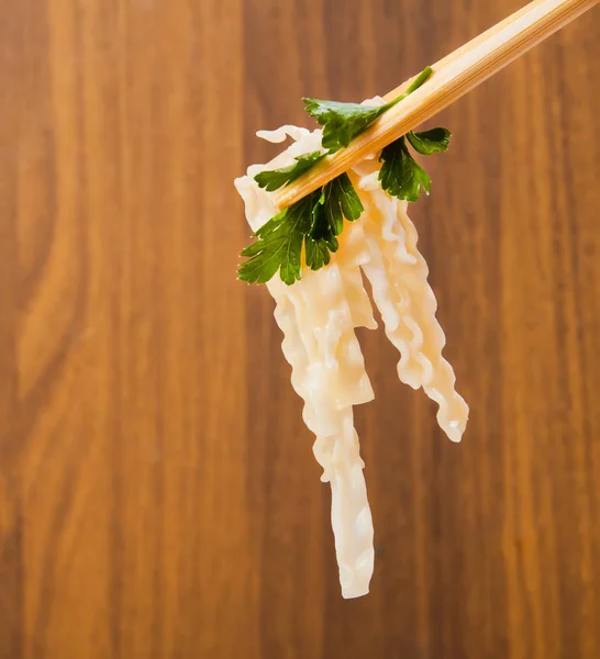 Espaguetis frescos con hoja verde en stics chinos de cerca sobre madera — Foto de Stock