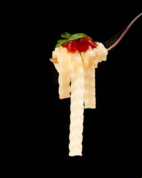 Espaguetis frescos con salsa de tomate rojo en tenedor de cerca en negro — Foto de Stock