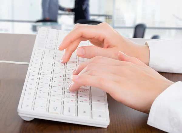 Naisen kädet kirjoittamalla valkoinen tietokone näppäimistö toimistossa — kuvapankkivalokuva