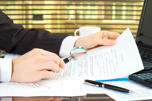 Vrouw handen met vergrootglas op zakelijke tafel met diagram — Stockfoto