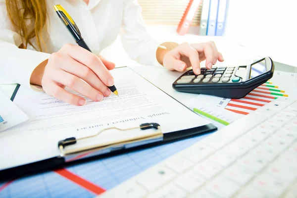 Güzel elleri olan kadın hesap makinesi ve klavye üzerinde çalışıyor.
