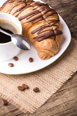 kahve ve kruvasan ahşap masa üzerinde plaka 