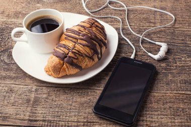 plaka ile kahve ve kruvasan ile akıllı telefon ve kulaklık woodentable 
