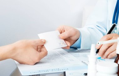 İşyerinde reçete yazarken hastaya tarifi veren doktor