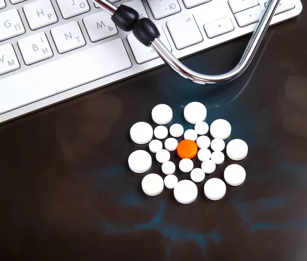 colorful pills on x-ray near keyboard and stethoscope, close-up
