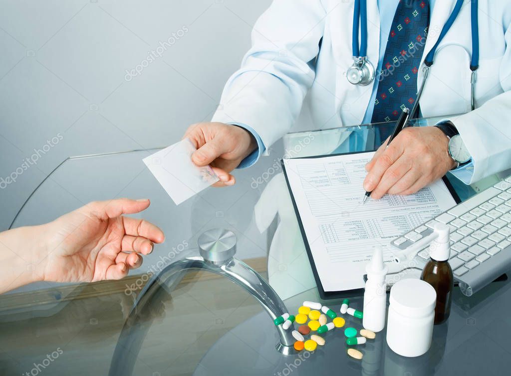 doctor giving recipe to patient while writing prescription at workplace