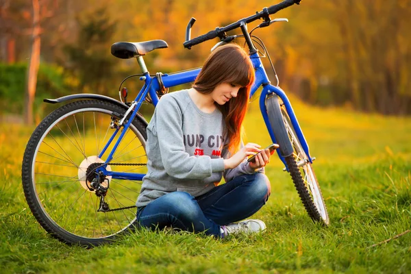 Piękna Młoda Kobieta Pomocą Telefonu Komórkowego Siedzący Obok Jej Rower — Zdjęcie stockowe