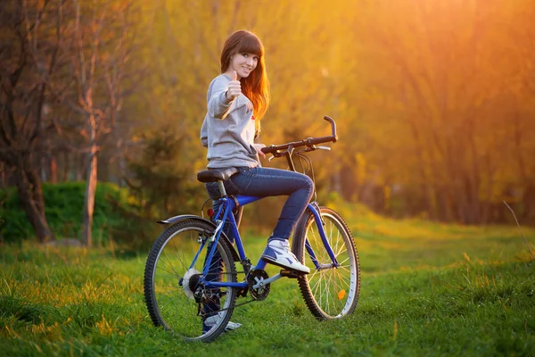 Красивая Улыбающаяся Девушка Сидящая Рядом Велосипедом Показывающая Знак Закате Лета — стоковое фото