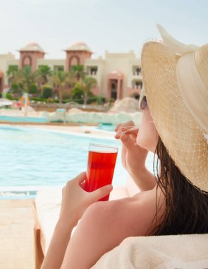 cosmopolitan kokteyl ile havuz başı, rahatlatıcı şapkalı kadın