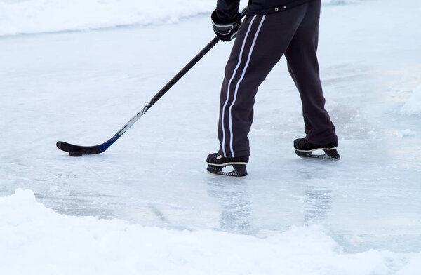 man with ice skates and stick on winter ice play hockey