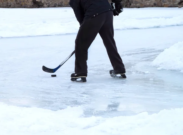 man with ice skates and stick on winter ice play hockey