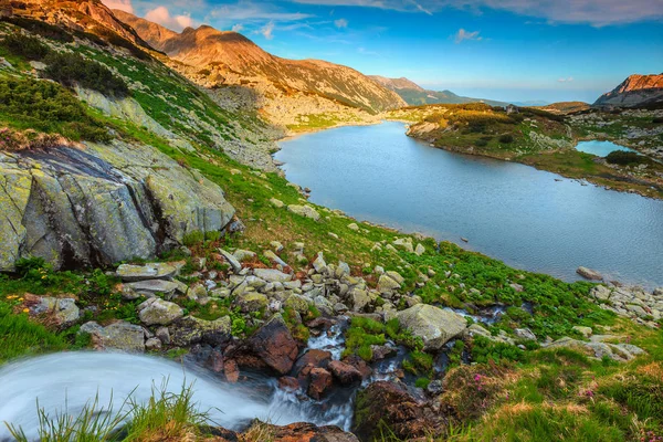Потрясающее альпийское озеро с водопадом в горах Ретезат, Трансильвания, Румыния — стоковое фото