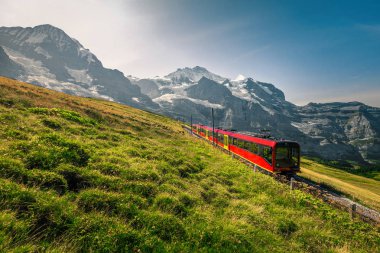 Elektrikli turist treni ve arka planda karlı Jungfrau dağları, İsviçre