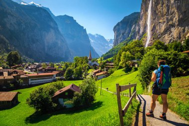 Sırt çantalı kadın yürüyüşçü Lauterbrunnen, İsviçre 'de manzaranın tadını çıkarıyor