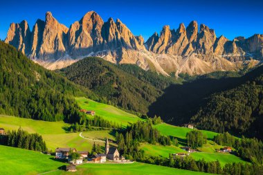 Yeşil yaz tarlaları ve yüksek dağlarla tepeden muhteşem bir manzara. Santa Maddalena köyü, Dolomitler, İtalya ve Avrupa 'da geleneksel dağlık kilise ve dağ çiftlikleriyle göz kamaştırıcı bir yer.