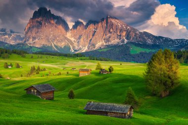 Günbatımında ahşap kulübeleri ve karlı dağları olan muhteşem bir dağ evi, Dolomitler, Alpe di Siusi tatil köyü, İtalya, Avrupa
