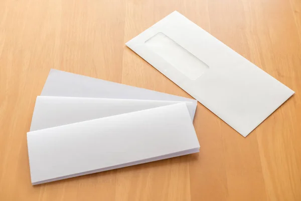 Four fold white template paper with white envelope on wood background — Stock Photo, Image