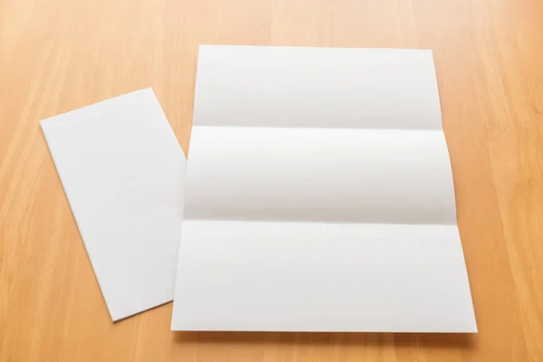 Tríptico papel de plantilla blanco sobre fondo de madera — Foto de Stock