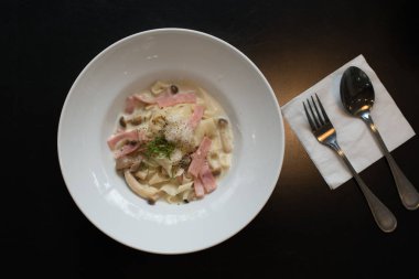 Spagetti krema sos jambon ve mantar beyaz çanak hizmet.