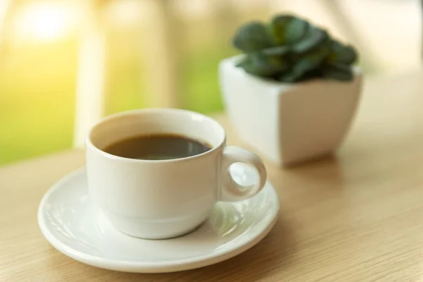 Café en tasse blanche sur table en bois avec lumière du soleil du matin — Photo