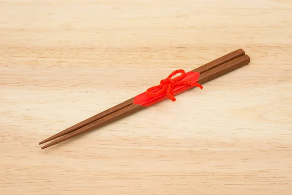 Japanese wooden chopsticks wrapped in red paper and red rope on — Stock Photo, Image