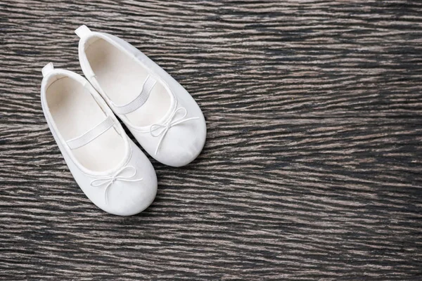 Zapato de bebé blanco sobre fondo de madera, vista superior — Foto de Stock
