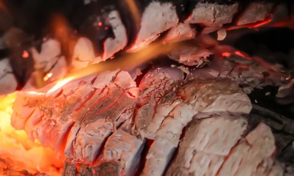 Alevler ve parlayan közle yanan bir şöminenin yanına.