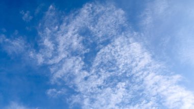 Derin, mavi bir yaz gökyüzünde huzurlu, yumuşak, beyaz bulutlar.