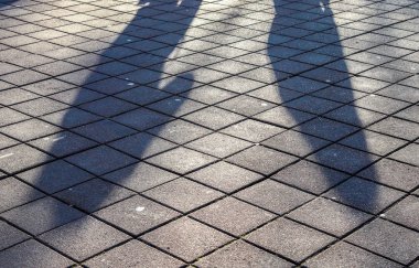 Alış veriş alanındaki kaldırım taşları üzerindeki insanların gölgeleri.